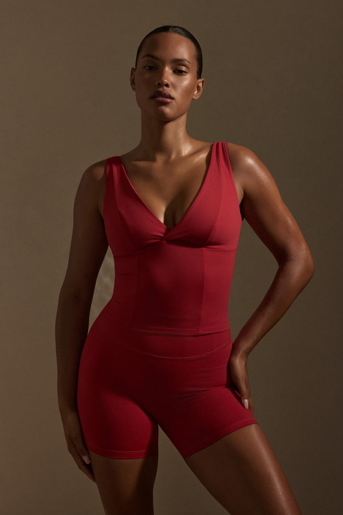 Three-quarter view of Glacier Tank in Cherry showing V-neck and adjustable straps on model against neutral background