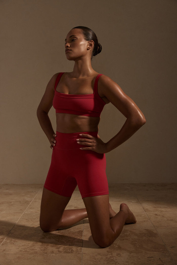 Front view of Griffith Short in Cherry showcasing high waist and doubled waistband with model kneeling on neutral studio floor