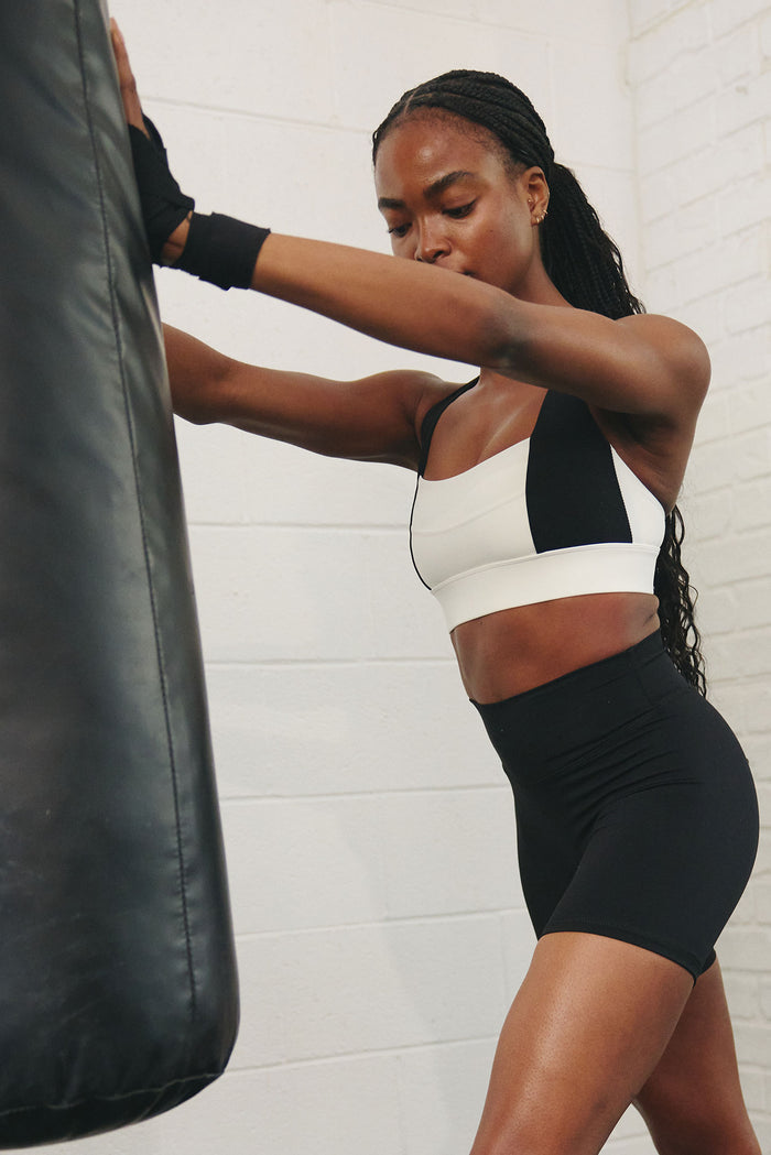 Angled view of Griffith Short 6.25in black showing high-rise waist and mid-thigh fit on model against a punching bag