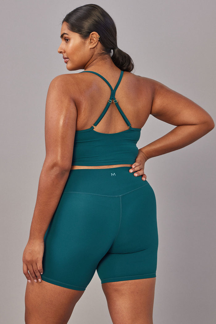 Back view of Griffith Short 6.25 in Evergreen showing high‑waist fit, center‑back M logo, and mid‑thigh length on gray background
