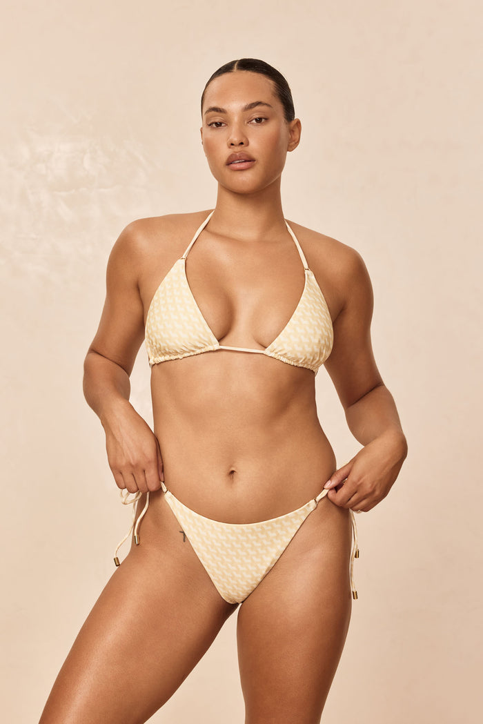 Front view of Hanalei Top in Ivory Geo showcasing triangle cups, removable padding, thin adjustable neck and back ties with gold rings on a beige background