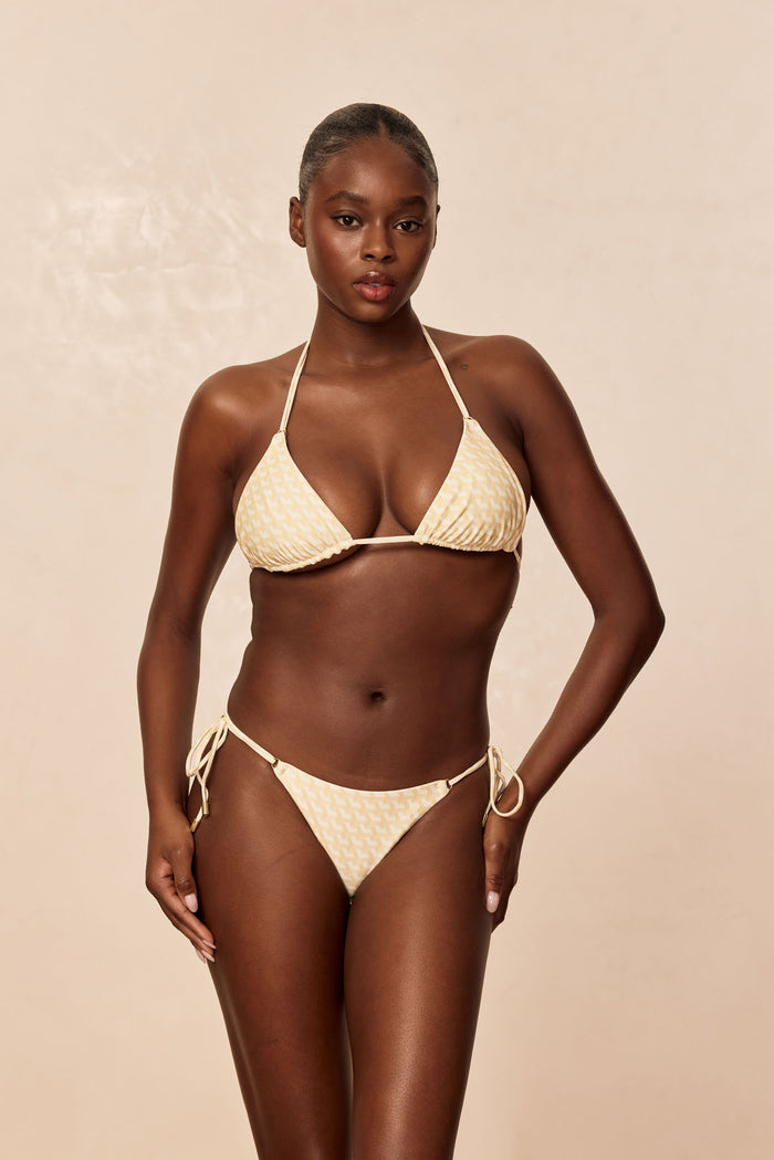 Front view of Hanalei Top in Ivory Geo on model with triangle cups, removable padding, adjustable thin ties and gold ring hardware on beige background
