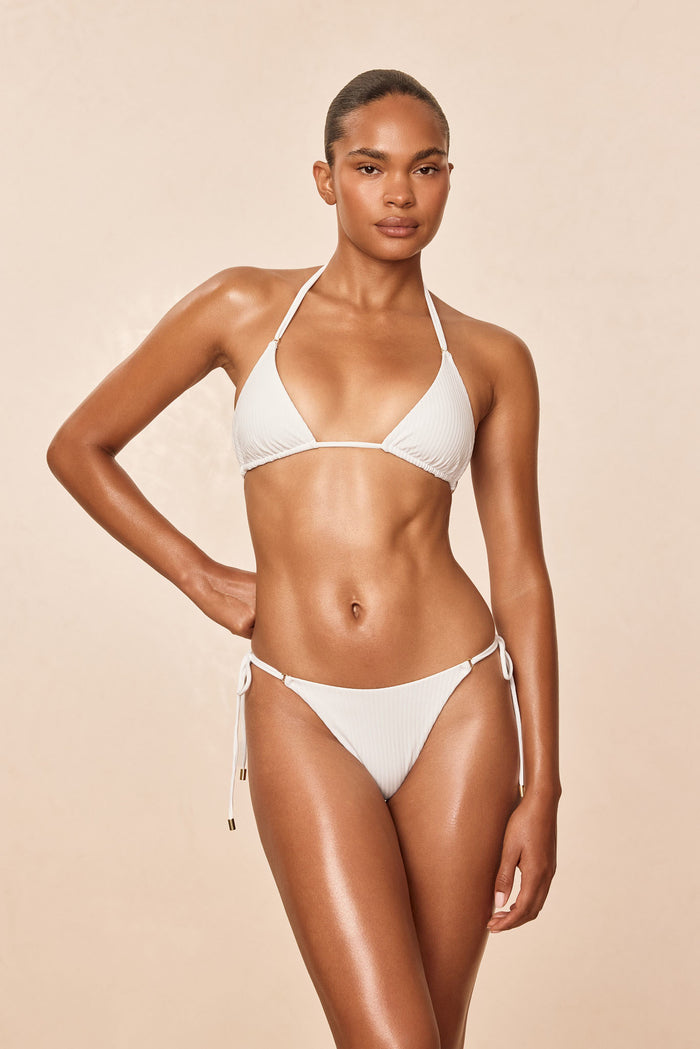 Front view of Hanalei Bottom in White Rib showing ribbed fabric and adjustable side ties with gold hardware on beige background