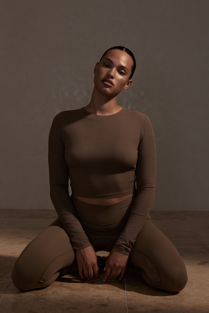 Front view of Hayworth Long Sleeve in Stone on a seated model, fitted cropped ribbed long-sleeve top against neutral background