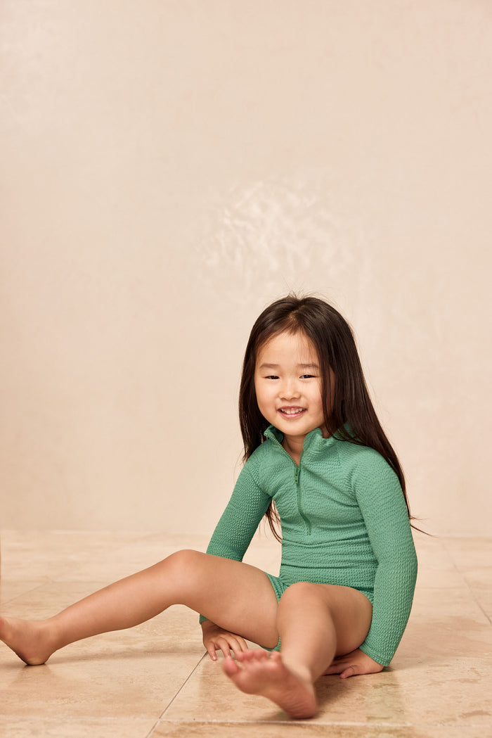Front view of Hilo One Piece Kids - Pond Crinkle with long sleeves, front zipper and scoop neckline on a child model