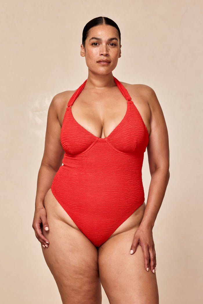 Front of Honolulu One Piece Chili Pepper Crinkle with underwire cups, adjustable halter tie and high-leg cut on beige backdrop