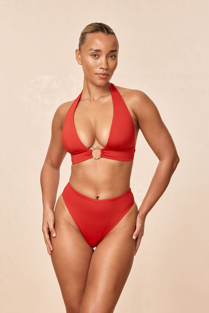 Front view of Ibiza Top in Chili Pepper on model, halter plunge with gold O ring center on beige background