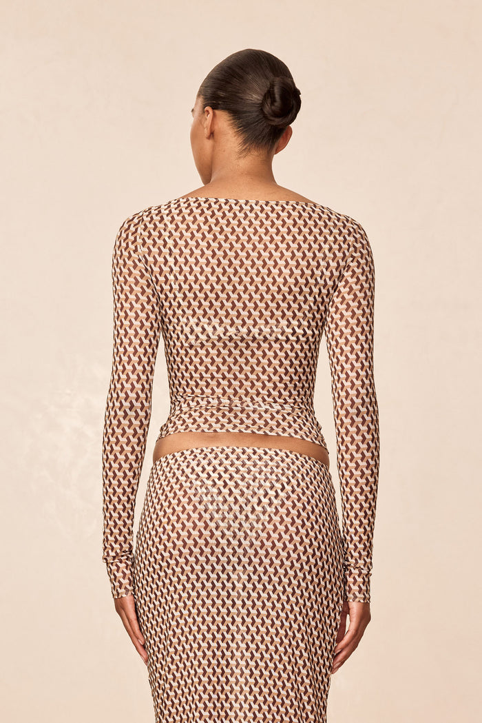 Back view of Ipanema Top Husk Geo Mesh showing sheer long sleeves and geometric print on model against beige background