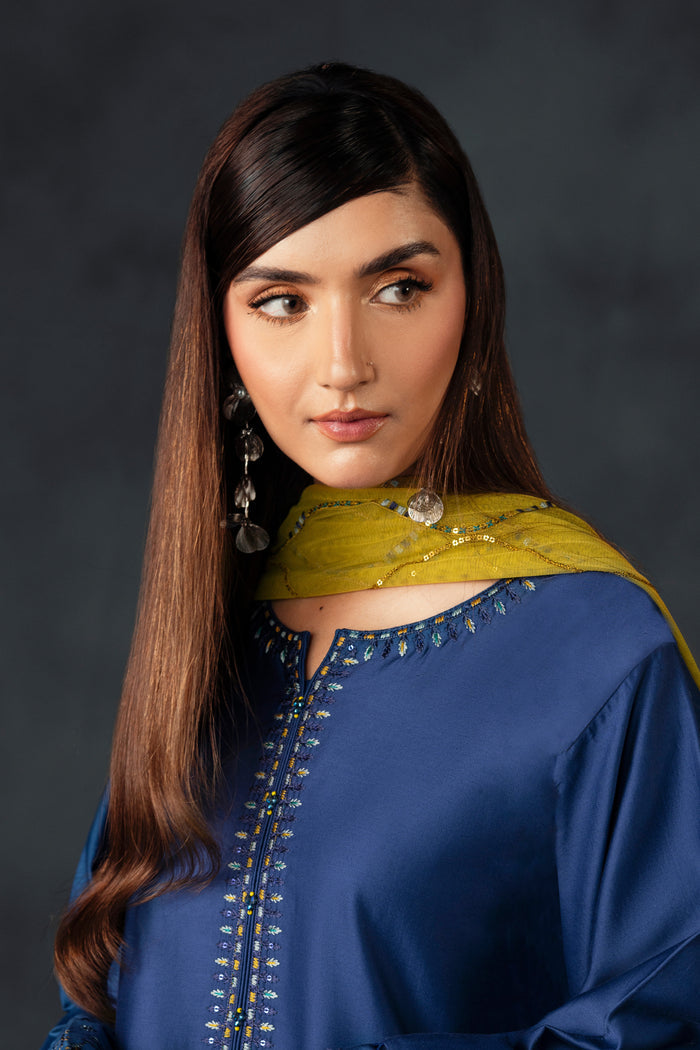 Portrait of NAQSHI Irha model wearing blue embroidered shirt with mustard net dupatta, styled for wedding and celebration