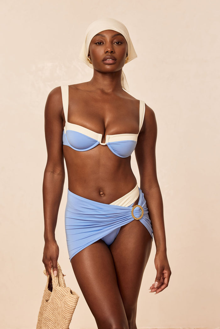 Front view of Cala Roja top in azure and ivory showing balconette underwire, straps, and contrast trim on beige background