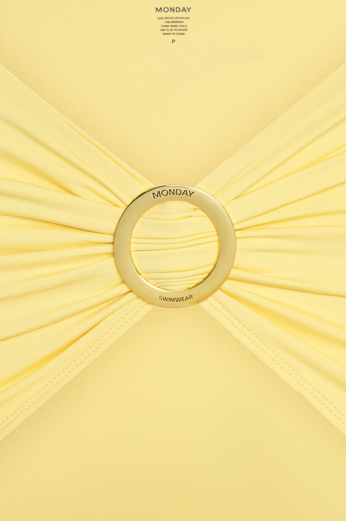 Close-up of Jamaica Sarong Meyer showing adjustable gold metal sliding buckle engraved MONDAY SWIMWEAR on pale yellow fabric