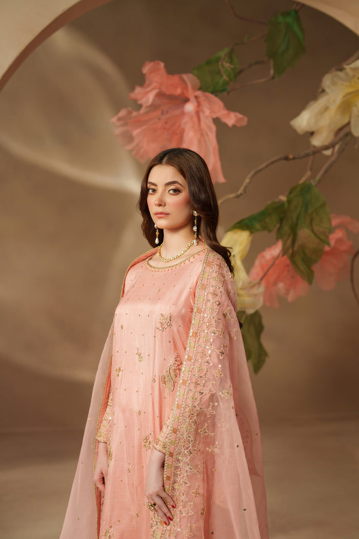 Model wearing NAQSHI Jinan peach pink luxury pret dress with embroidered details and light dupatta, giving a graceful event-ready look.