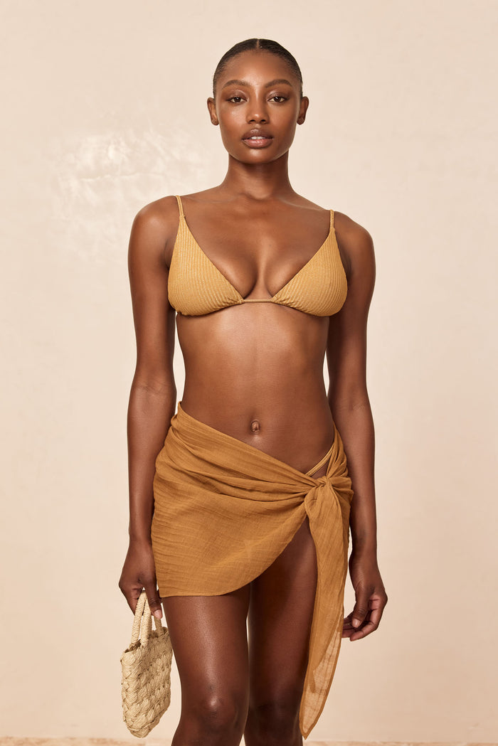 Front view of South Beach sarong in Antique Gold crinkle linen tied at the hip, short wrap with side knot on beige background