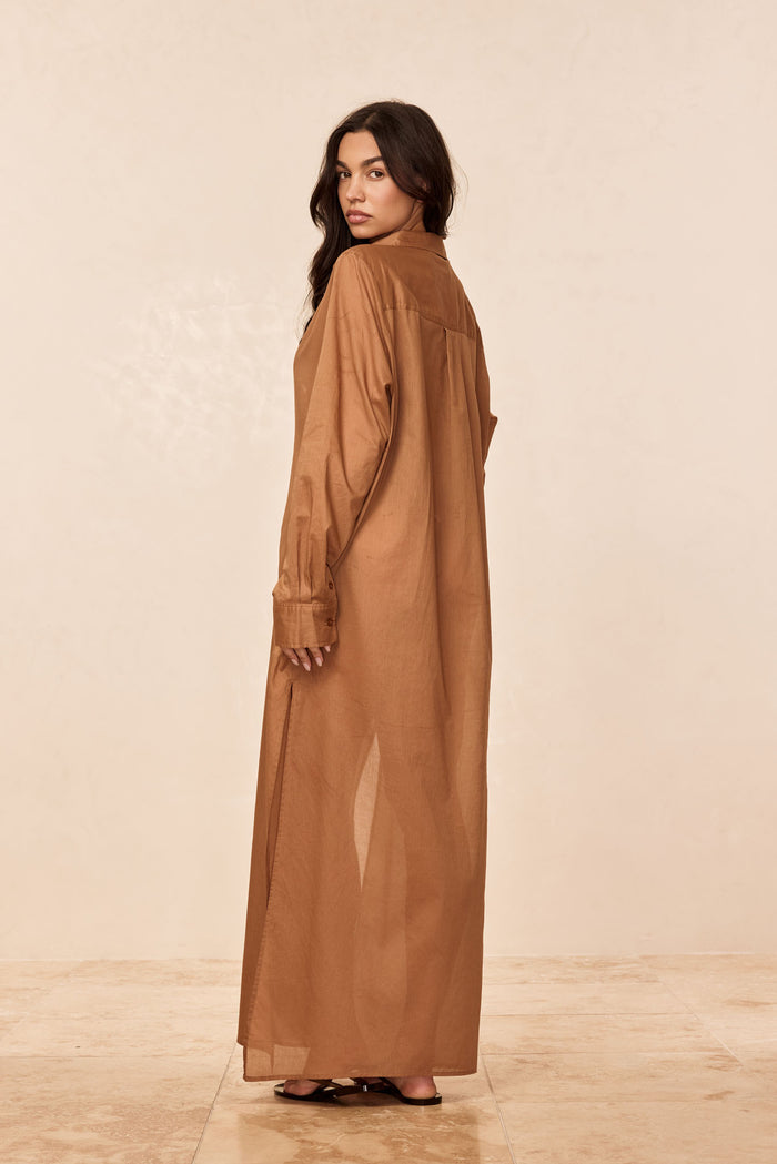 Rear three-quarter view of Kokomo Kaftan in caramel cotton voile showing relaxed maxi fit, long sleeves, back yoke and side slit on a neutral studio background