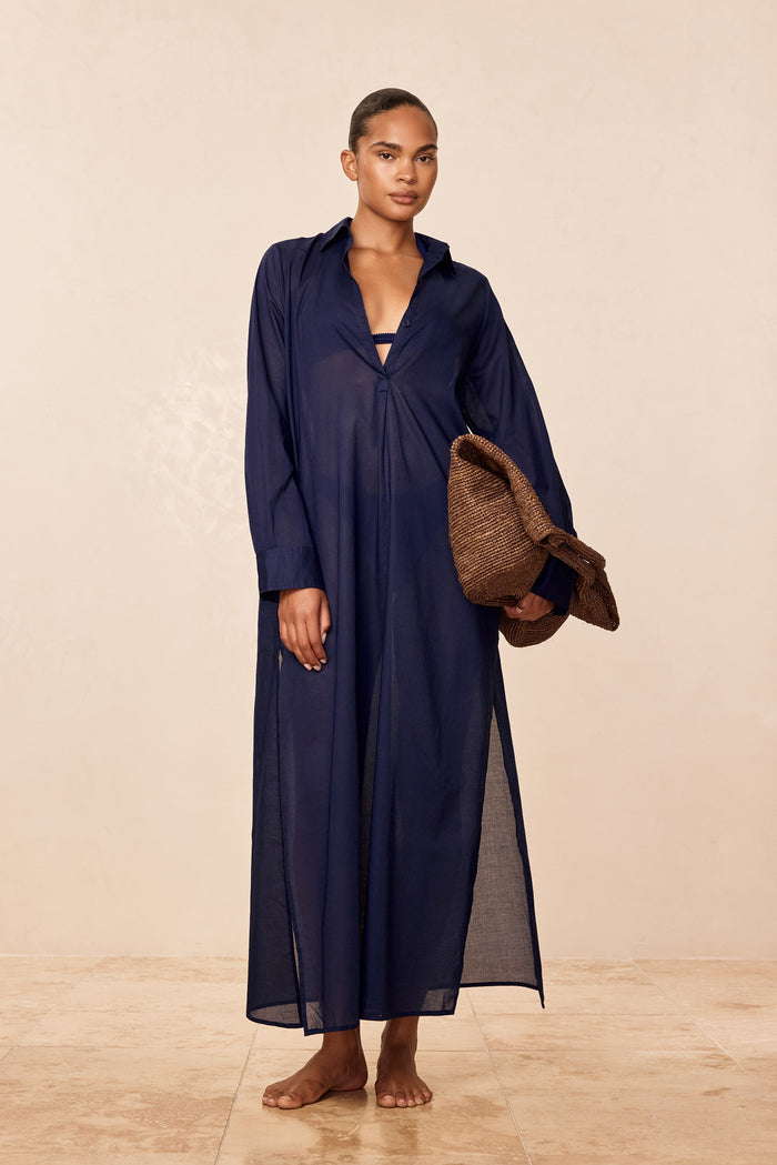 Front view of Kokomo Kaftan in Midnight Voile, semi-sheer ankle-length with long sleeves, model holding woven bag