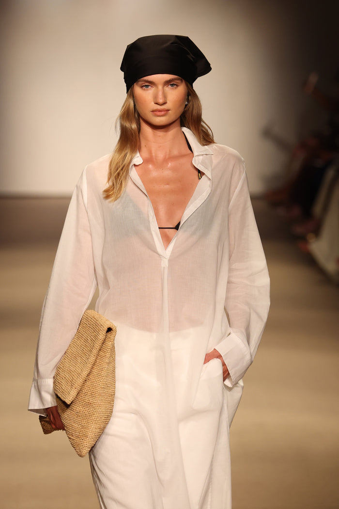 Front view of Kokomo Kaftan in white cotton voile showcasing semi-sheer fabric, pleated button-front and side pockets on runway