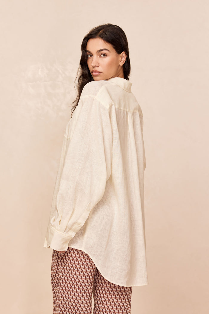 Back view of La Jolla Linen Shirt in ivory showing oversized fit, curved hem, and linen texture on model, beige background