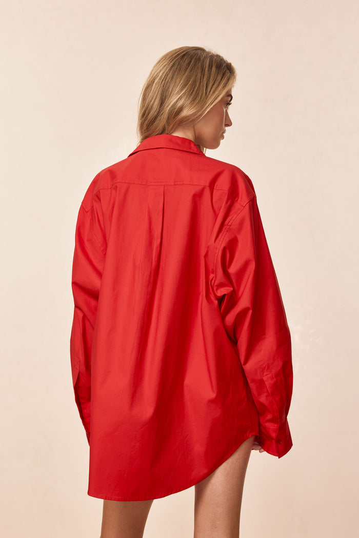 Back view of La Jolla shirt in chili pepper showing oversized fit, long sleeves, and center back pleat on beige background