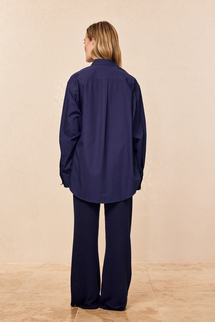 Back view of La Jolla Shirt in Midnight, showing oversized relaxed fit, long sleeves, collar, and curved hem on beige background