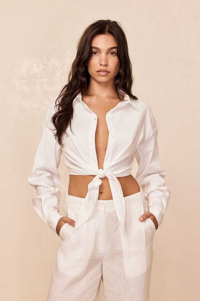 Front view of La Jolla Tie Shirt in white showcasing cropped tie-front, semi-sheer fabric and long sleeves on beige backdrop
