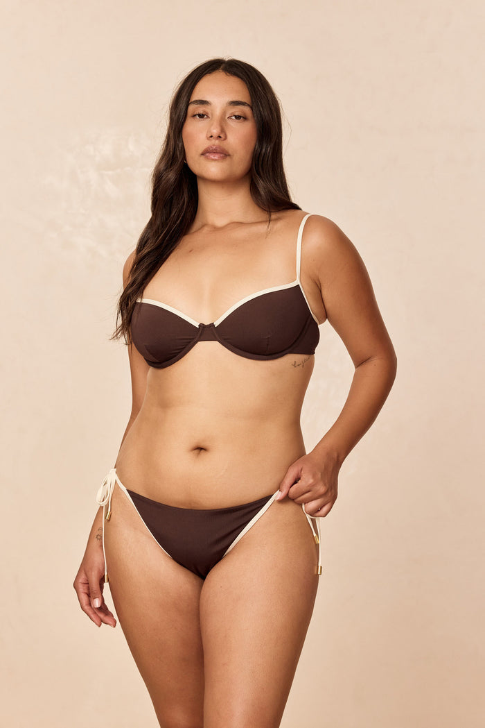 Front view of Le Marais Bottom in espresso with ivory trim on model showing tie-side adjustable fit against a beige background