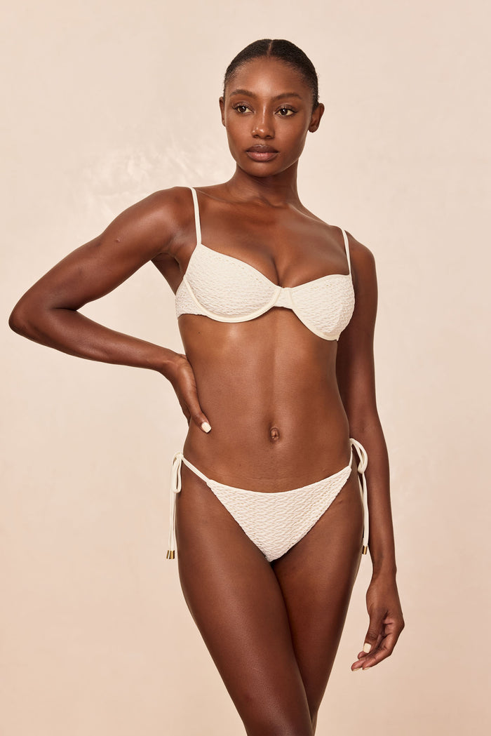 Front view of Le Marais Bottom in Ivory Crochet showcasing crochet texture and side ties on beige background