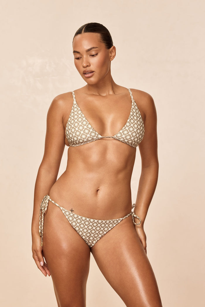 Three-quarter view of Le Marais tie-side bottom in Tile Geo print showing low-rise fit on model against beige background