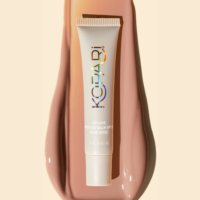 Top-down view of Lip Love Moisture Balm tube, Nude Beige SPF 30, resting on a smear of matching nude-beige balm