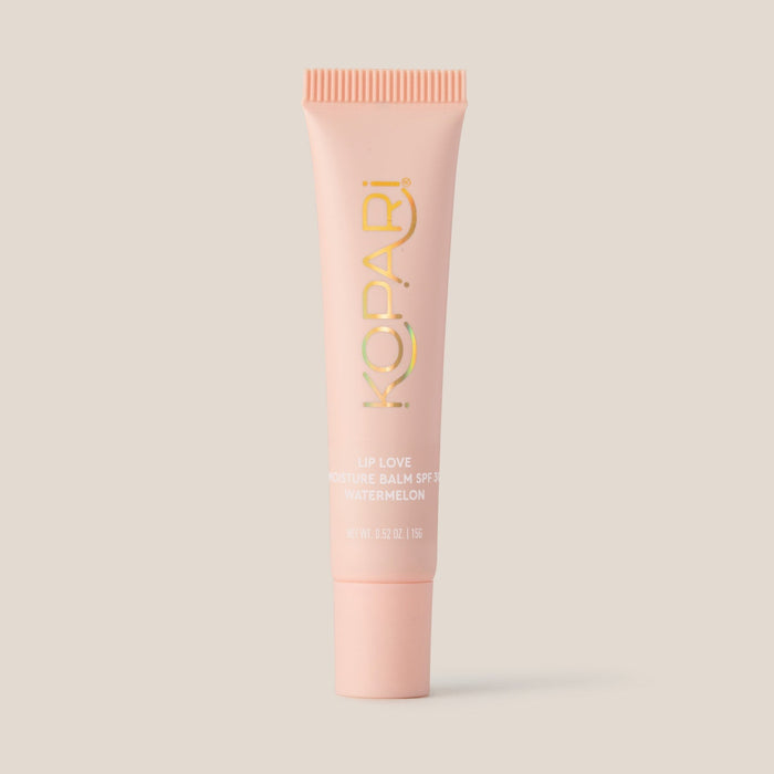 Front view of Kopari Lip Love moisture balm tube showcasing gold logo and Watermelon SPF 30 label on pale beige background