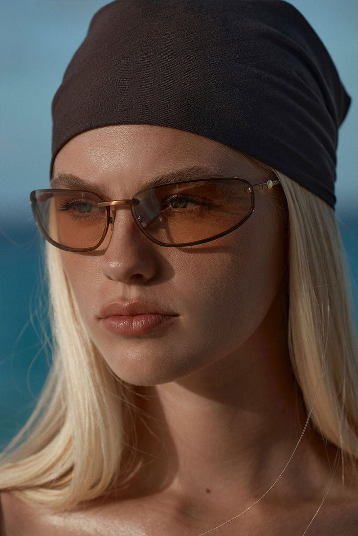 Front close-up of Malta sunglasses in bronze with brown gradient lenses and tortoise arms against sea