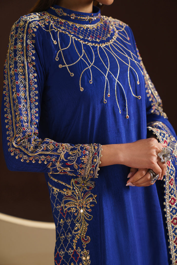 Model wearing full Naqshi Manvi 3PC set: royal-blue embellished raw-silk shirt, straight trousers and ornate dupatta styled for formal elegance.