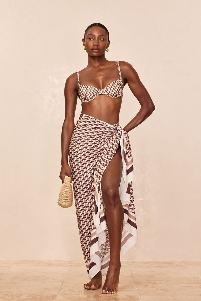 Front view of Marina Piccola Sarong Husk Geo in brown-and-ivory geometric print, tied at the hip with a high side slit on a neutral beige backdrop