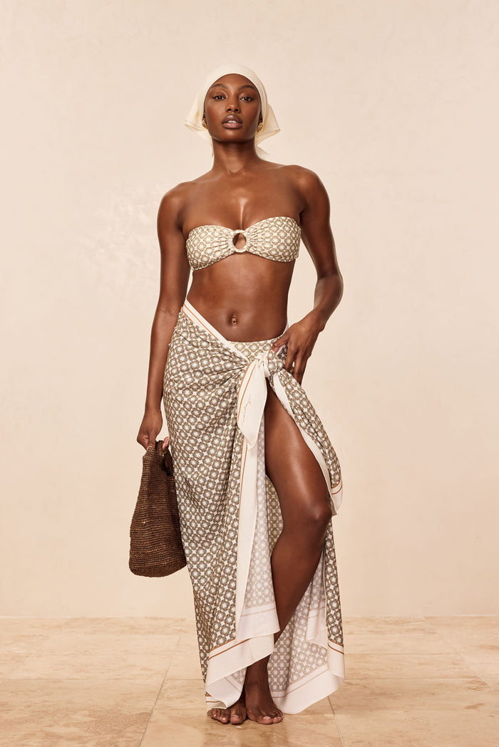 Front view of Marina Piccola sarong in Tile Geo print tied at the hip showing a thigh-high slit on a beige studio background