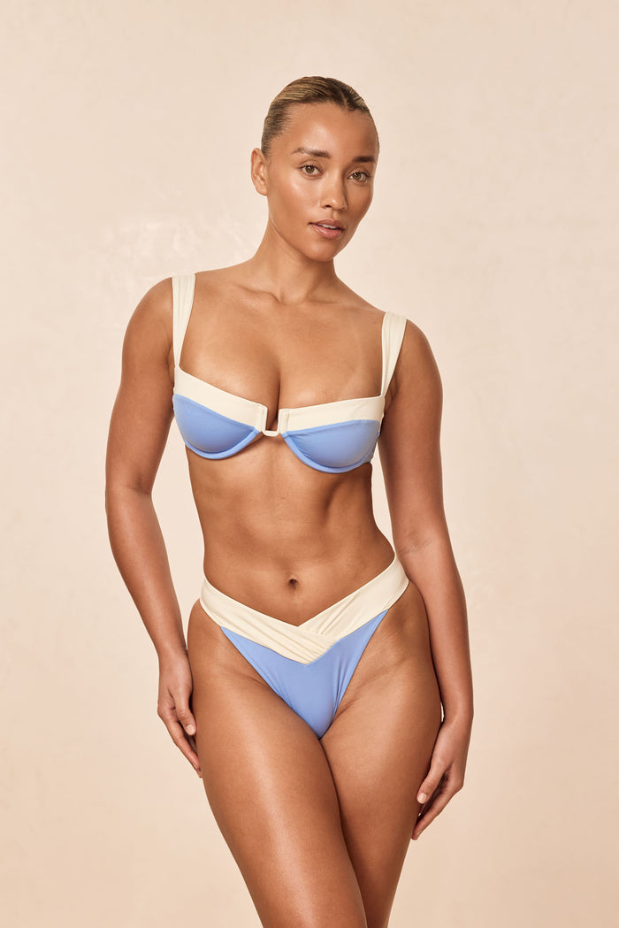 Front view of Cala Roja Top in Azure/Ivory showcasing underwire balconette cups and wide straps on beige background