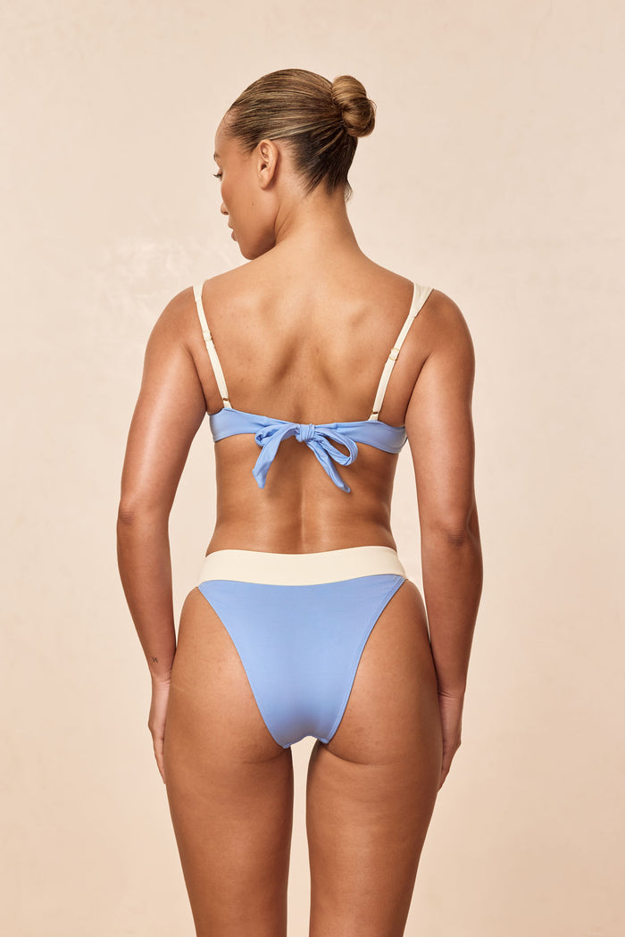 Back view of Cala Roja top in azure and ivory showcasing adjustable shoulder straps and tie-back on a beige background