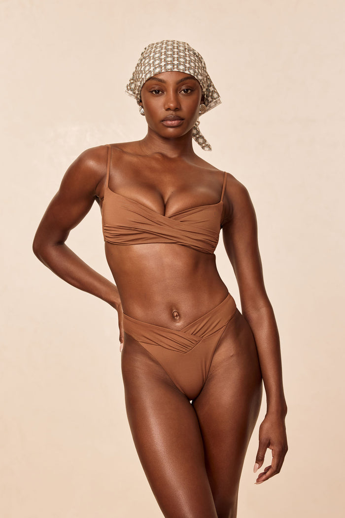 Front view of Marseille Bottom in caramel showcasing V-shaped crossover waistband and high-cut legs on beige background