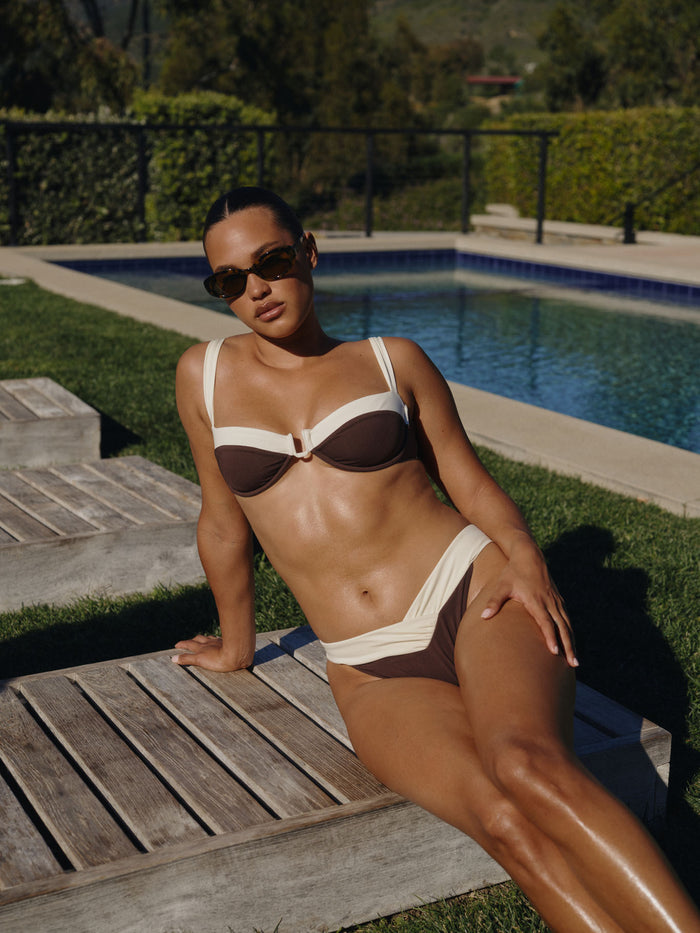 Angled view of Marseille Bottom in Espresso and Ivory on model showcasing color-block V-front waist and high-leg cut by a pool