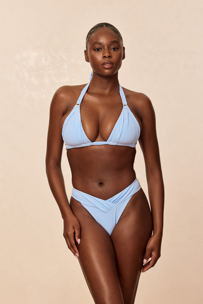 Front view of Marseille bottom in Sky Rib with V-front shirring, high-leg cut and cheeky coverage against beige background