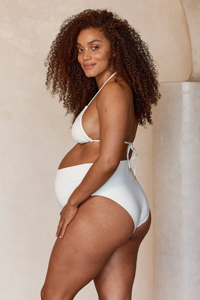 Side view of Maternity Riviera Bottom in Ivory showing high-rise maternity coverage and ruched sides on neutral background