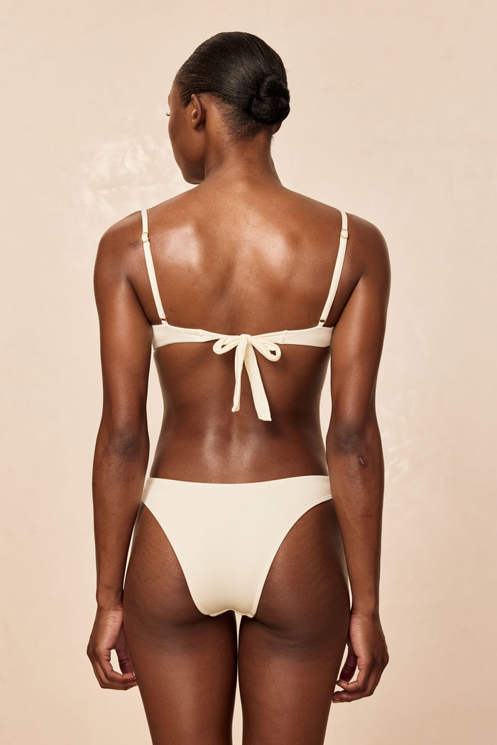 Rear view of Maui Top in ivory showcasing tied bow back and adjustable straps with neutral beige studio background