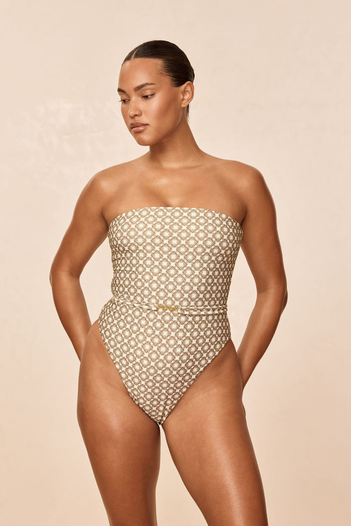 Three-quarter front of Miami One Piece - Tile Geo showing strapless bandeau top, high-cut leg and tile geometric print on neutral background