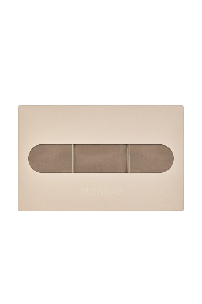 Front view of Monday G String 3-pack in caramel showing three folded g-strings visible through a beige box window on white background