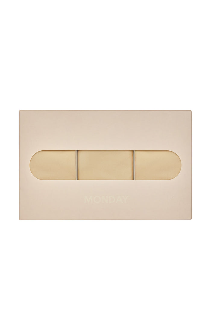 Front view of G-string three-pack in cashmere showing thin sides and minimal coverage in a beige display box on white background