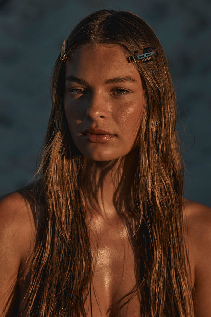Close-up of Monday Hair Clips on model showing a tortoiseshell clip labeled MONDAY and an ivory clip on wet hair