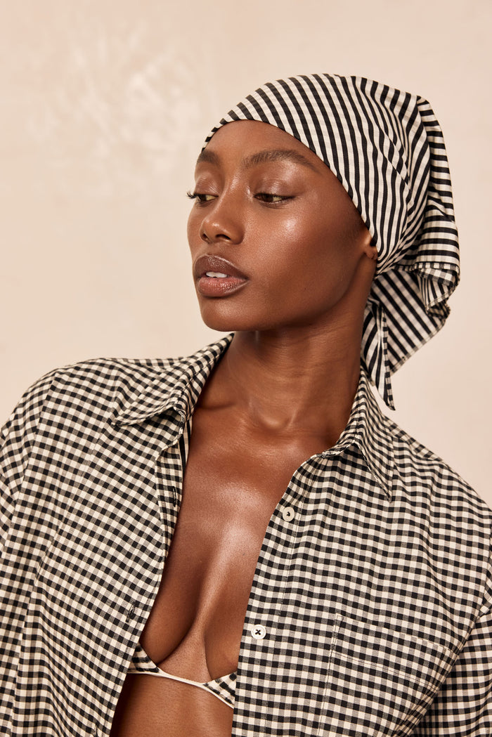 Close-up of Monday Head Scarf in black gingham showcasing tied drape and check pattern on a neutral beige background