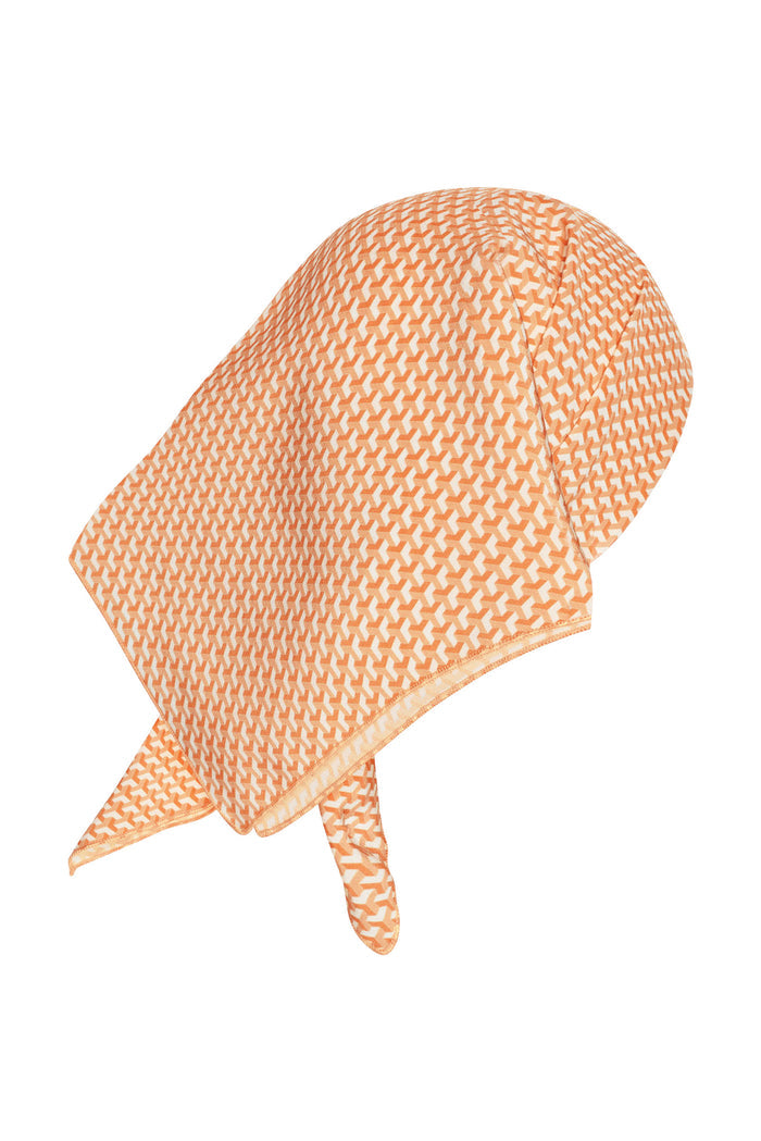 Angled view of Monday Head Scarf Micro Geo Silk showing orange micro-geo pattern on a square silk scarf against a white background