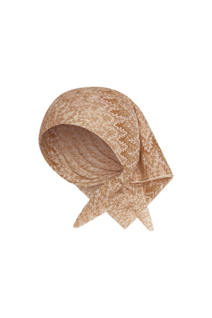 Angled view of Monday Head Scarf Porto Cervo Gold showcasing metallic gold textured pattern and tied corner on white background