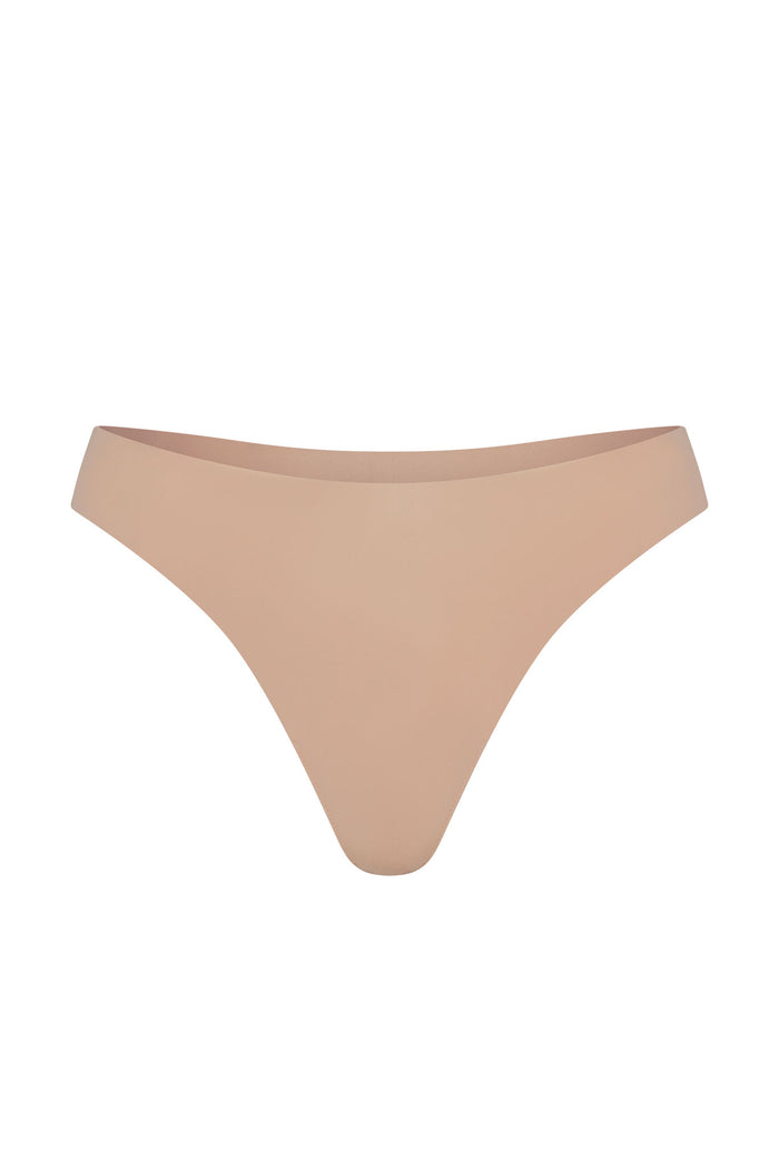 Front view of Invisible Thong in blush showcasing mid-rise fit and raw-edge minimal-coverage design on white background