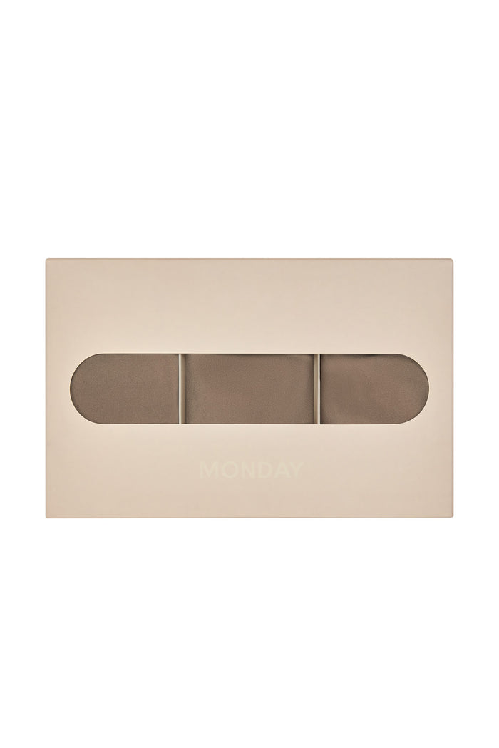 Front view of Monday Invisible Thong 3-pack in caramel showing three thongs visible through the box window on a white background