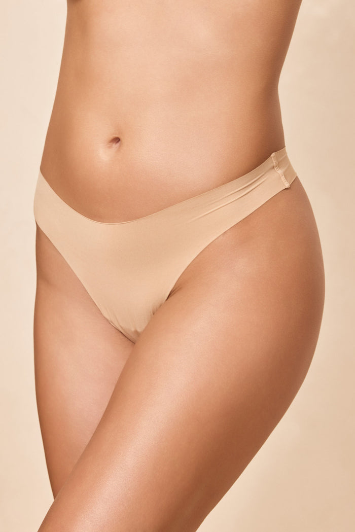 Front three-quarter view of Invisible Thong in Cashmere on model showcasing mid-rise fit and raw-edge seamless finish